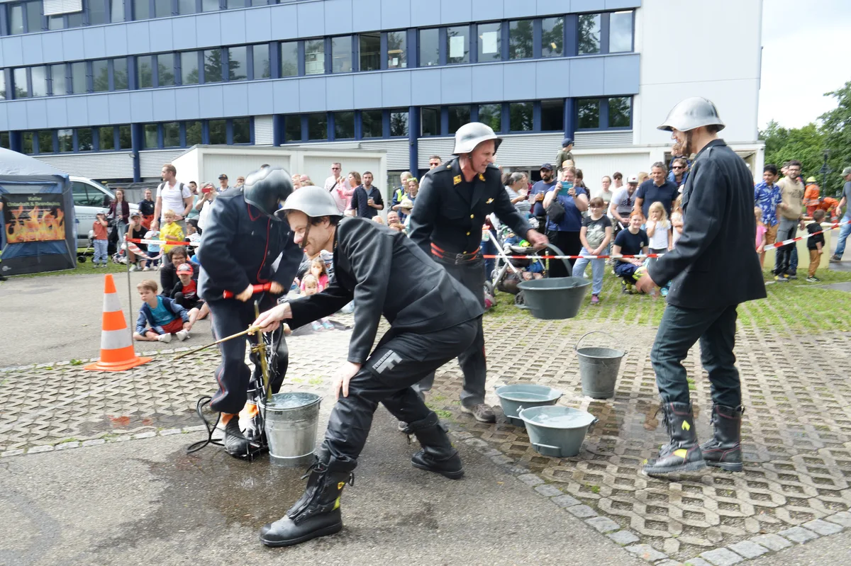 Männer in alten Uniformen spritzen mit Wasser. 
